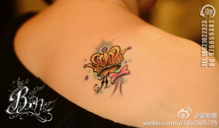 女生肩膀处小巧潮流的皇冠蝴蝶结纹身图案